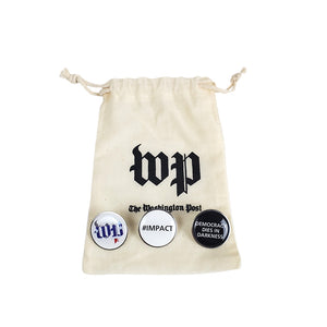 Off-white canvas drawstring bag with WP logo in black and The Washington Post below in black. Three circular pins with, left to right, WP colored like the American flag on a white background, the text #IMPACT in black on a white background and the text Democracy Dies in Darkness in white on a black background.