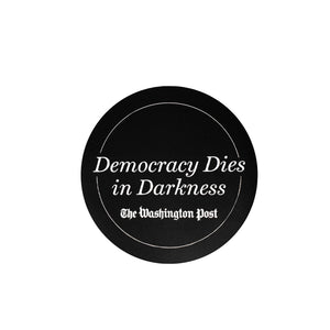 Circular black magnet with white line border and Democracy Dies in Darkness in large white text with The Washington Post in small white text below it.